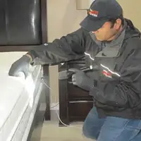 Bed bug inspection technician checking a mattress and bed frame for signs of infestation in Green Bay, WI