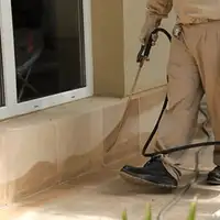 General pest control technician spraying exterior perimeter around a home in Green Bay, WI