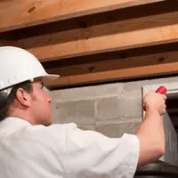 Termite inspection technician checking a basement wall and framing for termite activity in Green Bay, WI