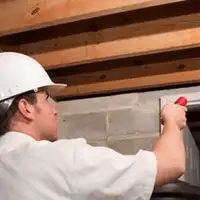 Termite inspection technician checking a basement wall and framing for termite activity in Green Bay, WI
